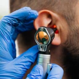 An ENT doctor using an otoscope to perform an ear exam.