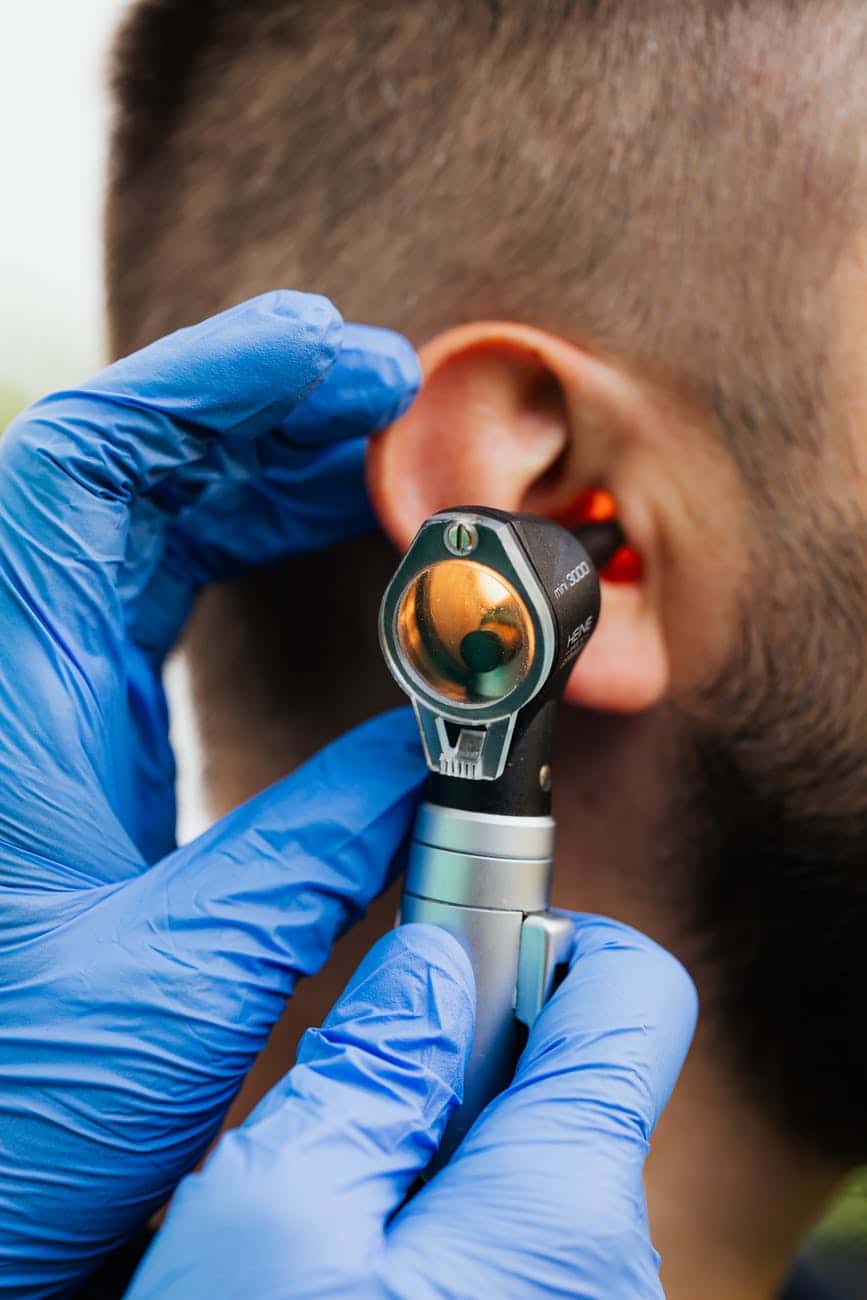 An ENT doctor using an otoscope to perform an ear exam.