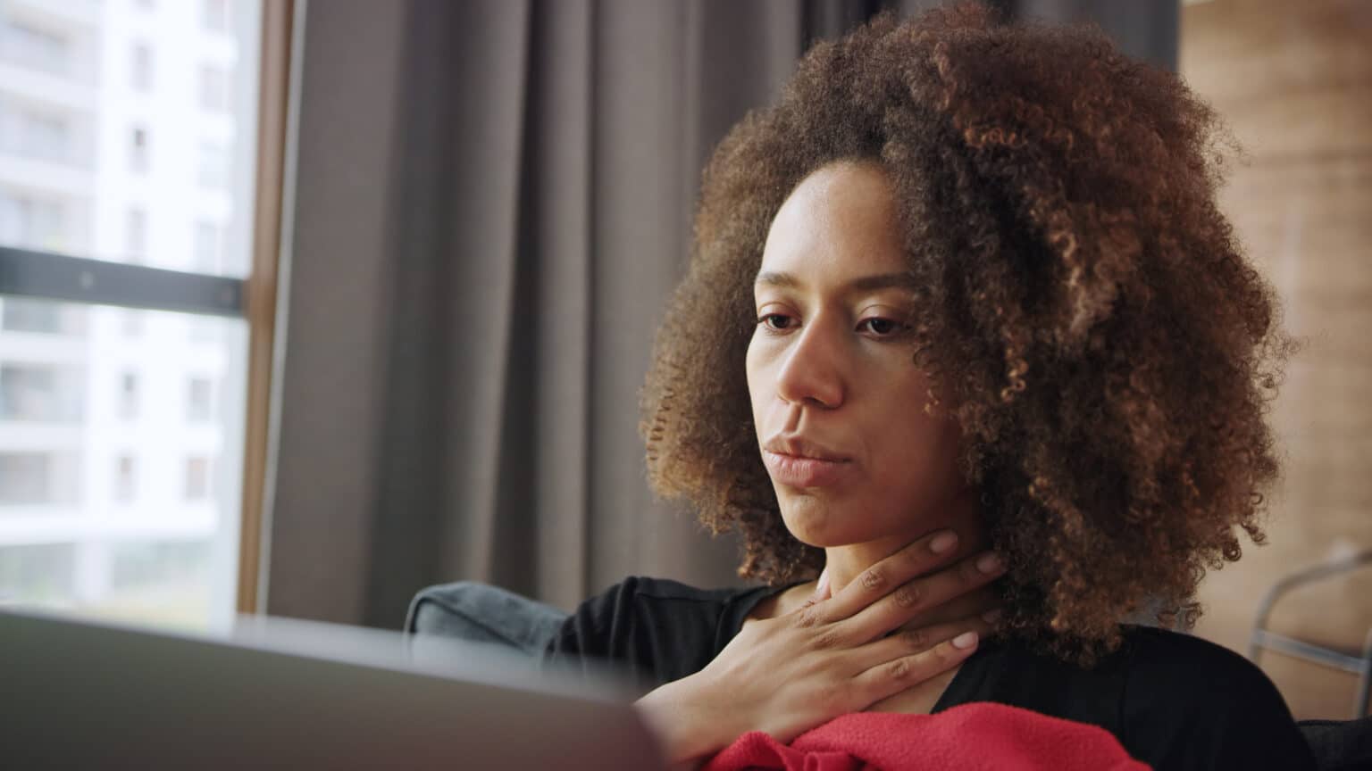 Woman with a sore throat resting at home.