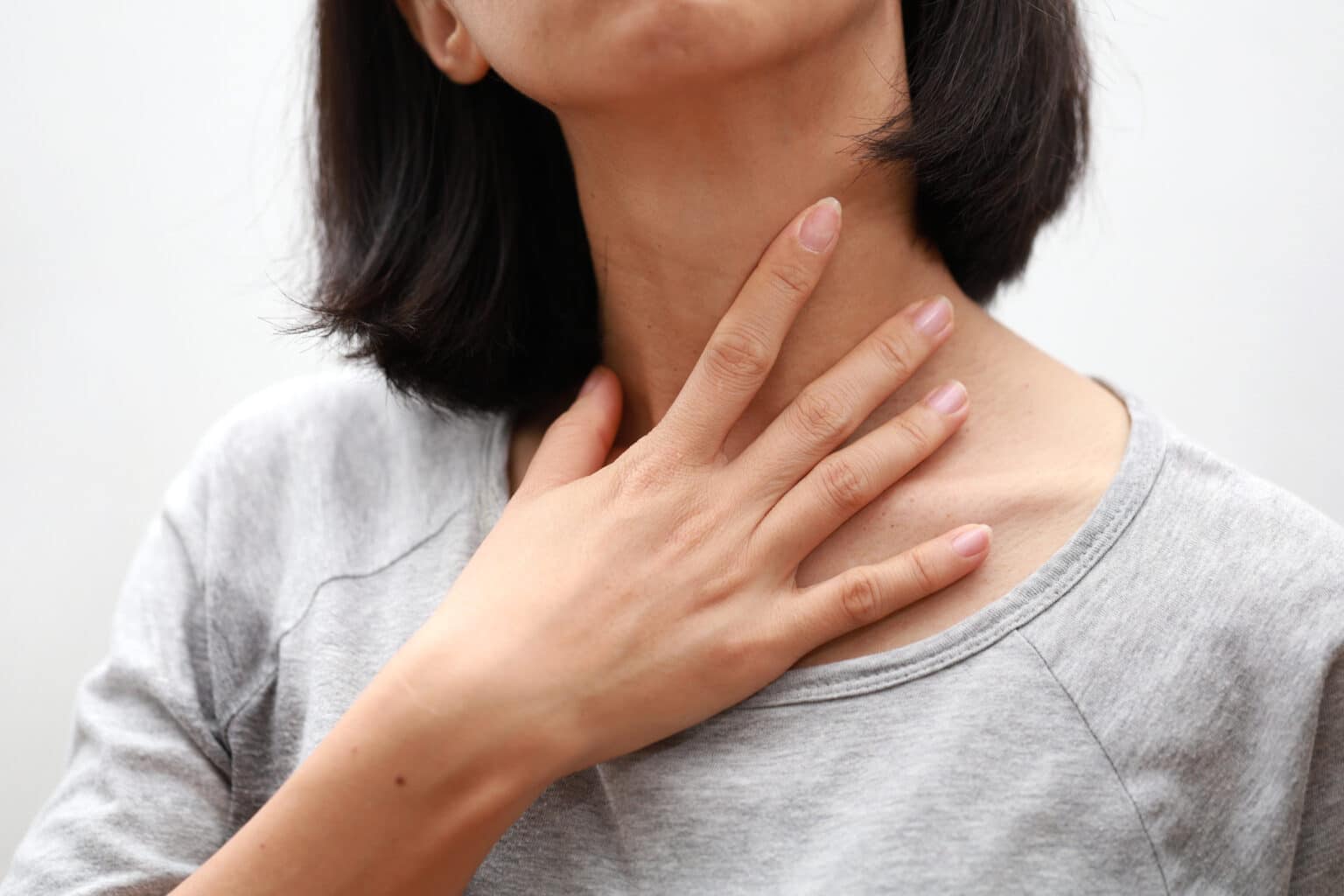 Close up of a woman touching her sore throat.