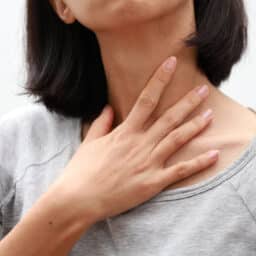 Close up of a woman touching her sore throat.