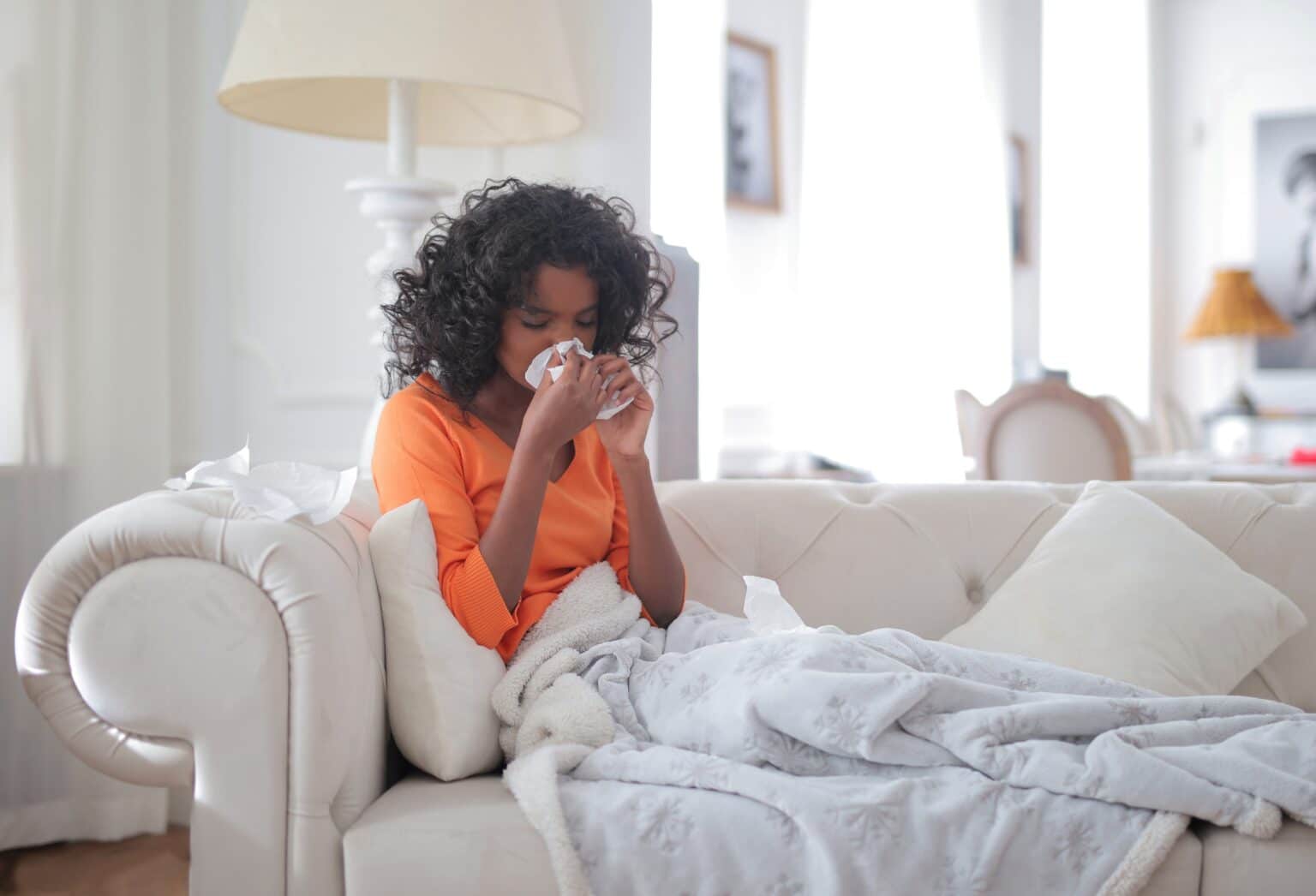 Woman with a sinus infection blowing her nose.