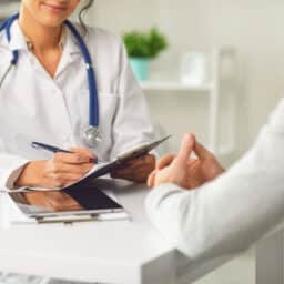 A doctor speaks with her patient in an ENT medical office setting.