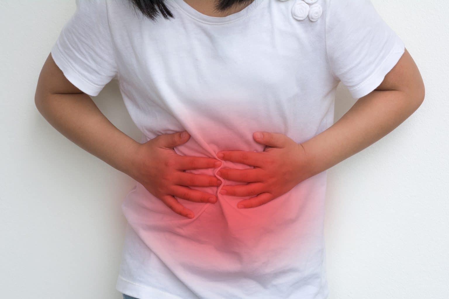 a young girl holds her stomach in discomfort