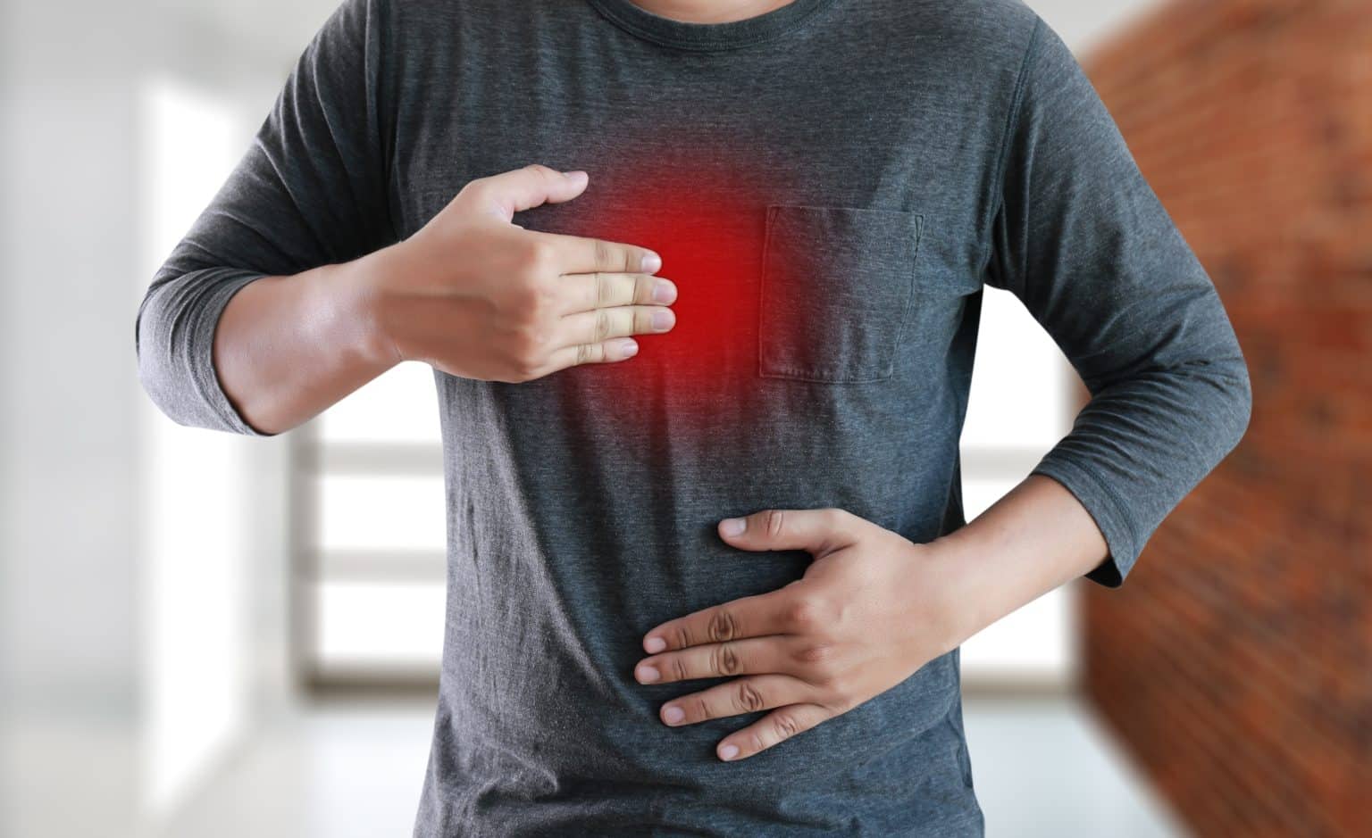 a man holds his stomach and chest in discomfort