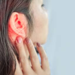 Young woman with ear pain touching ear.