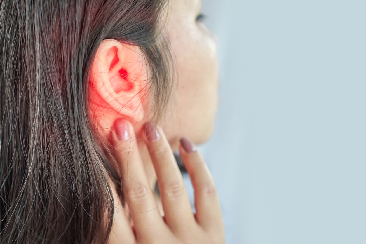 Young woman with ear pain touching ear.