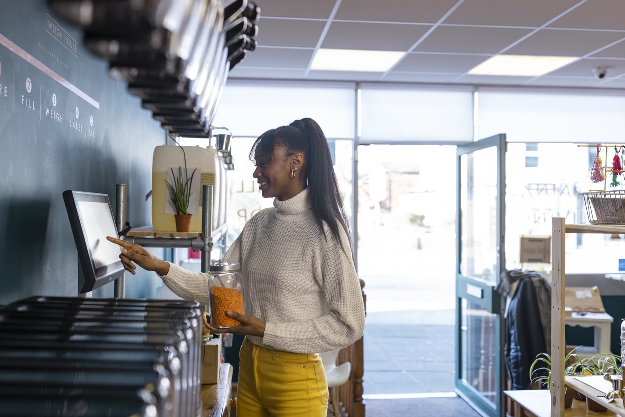 Woman using self checkout at a refill grocery store