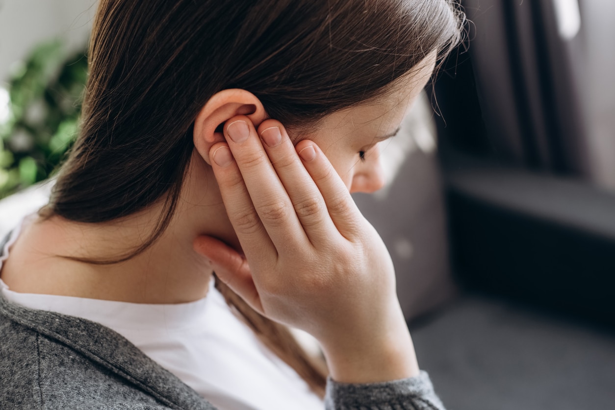 Woman holding her ear with an ear infection.
