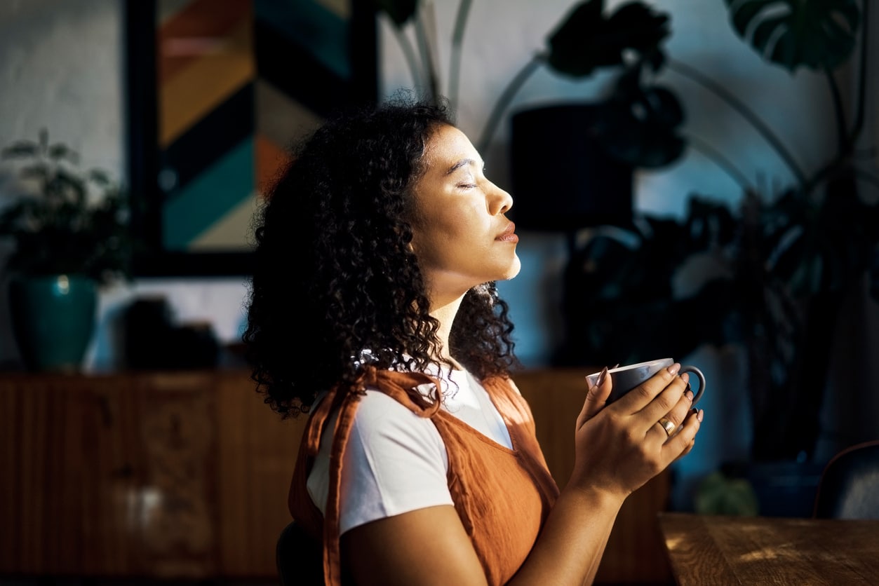 Woman holding a couple of tea with her eyes closed.