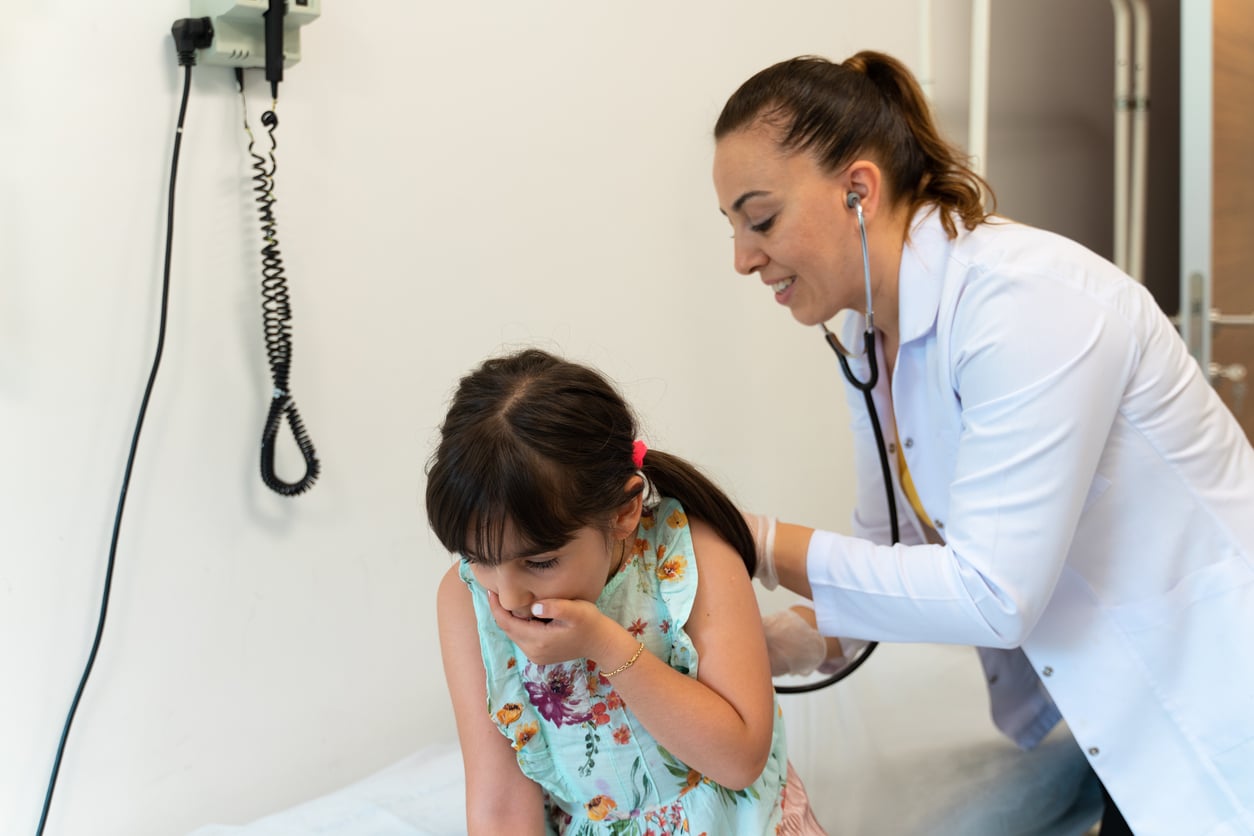 Coughing child being examined by a doctor.