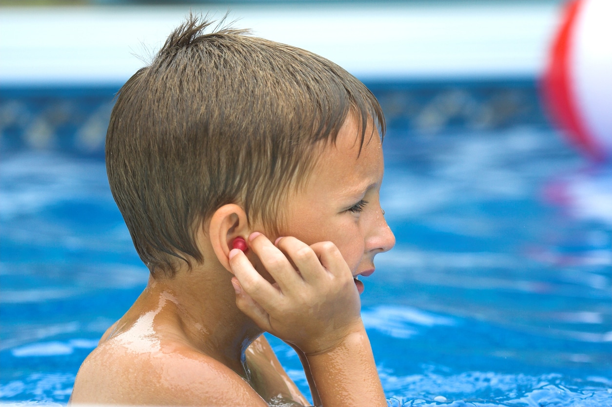 Boy adjusts water earplugs