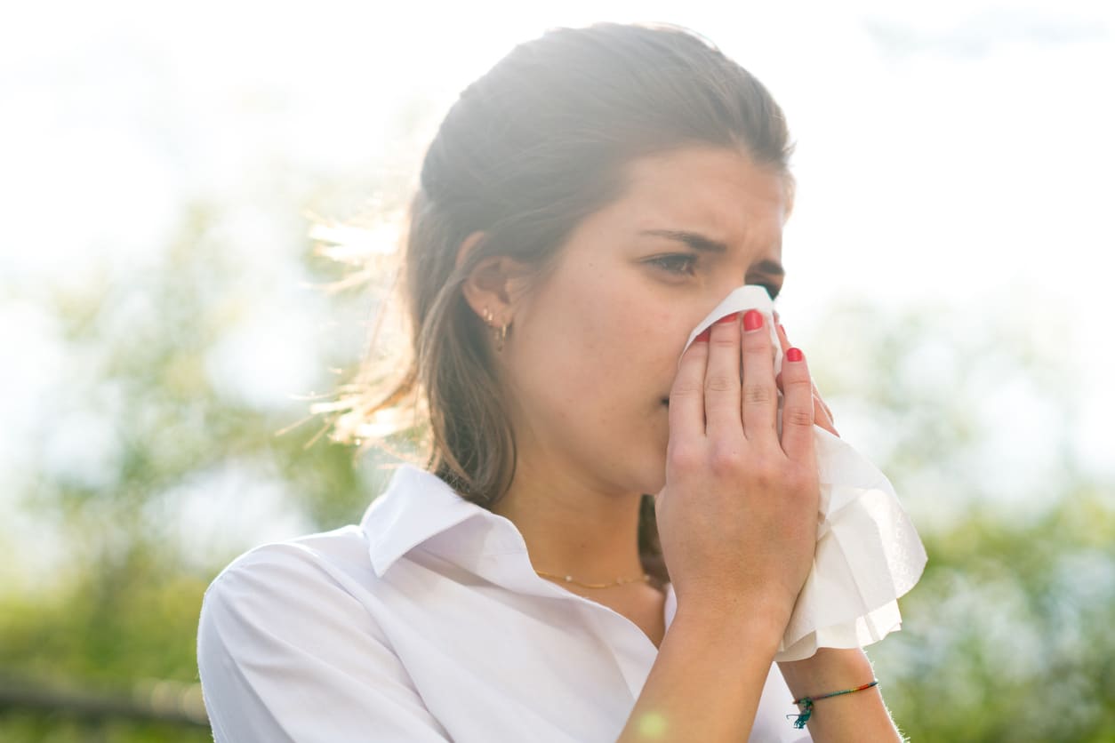 Woman blowing her nose outside.