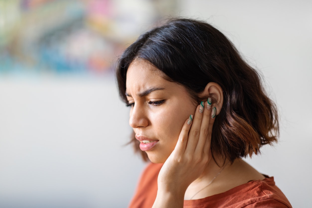 Woman with ear infection holds ears