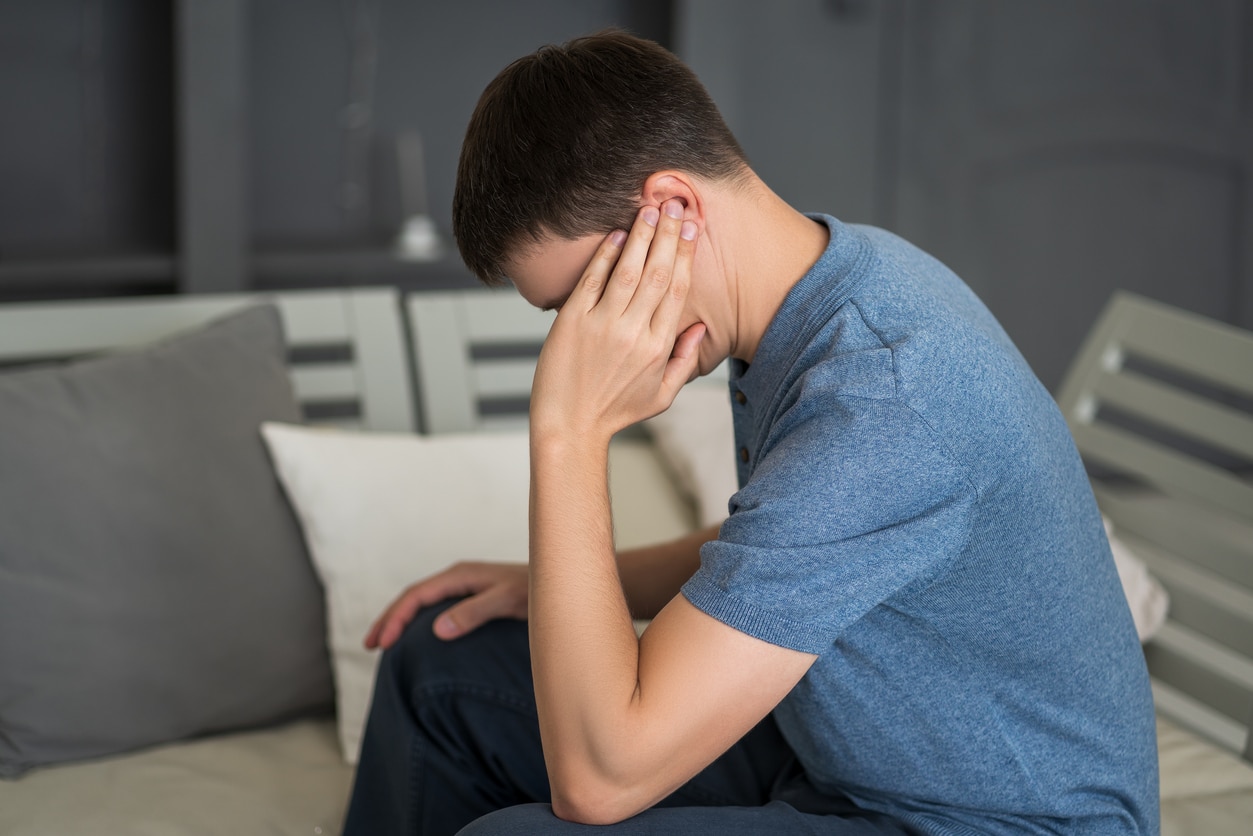 Young man holding his ear.