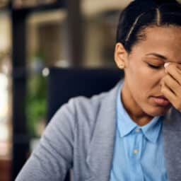 Woman with a sinus infection holding her nose due to the discomfort of sinus pressure.