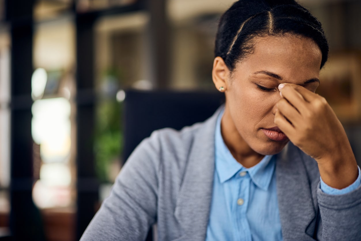 Woman with a sinus infection holding her nose due to the discomfort of sinus pressure.